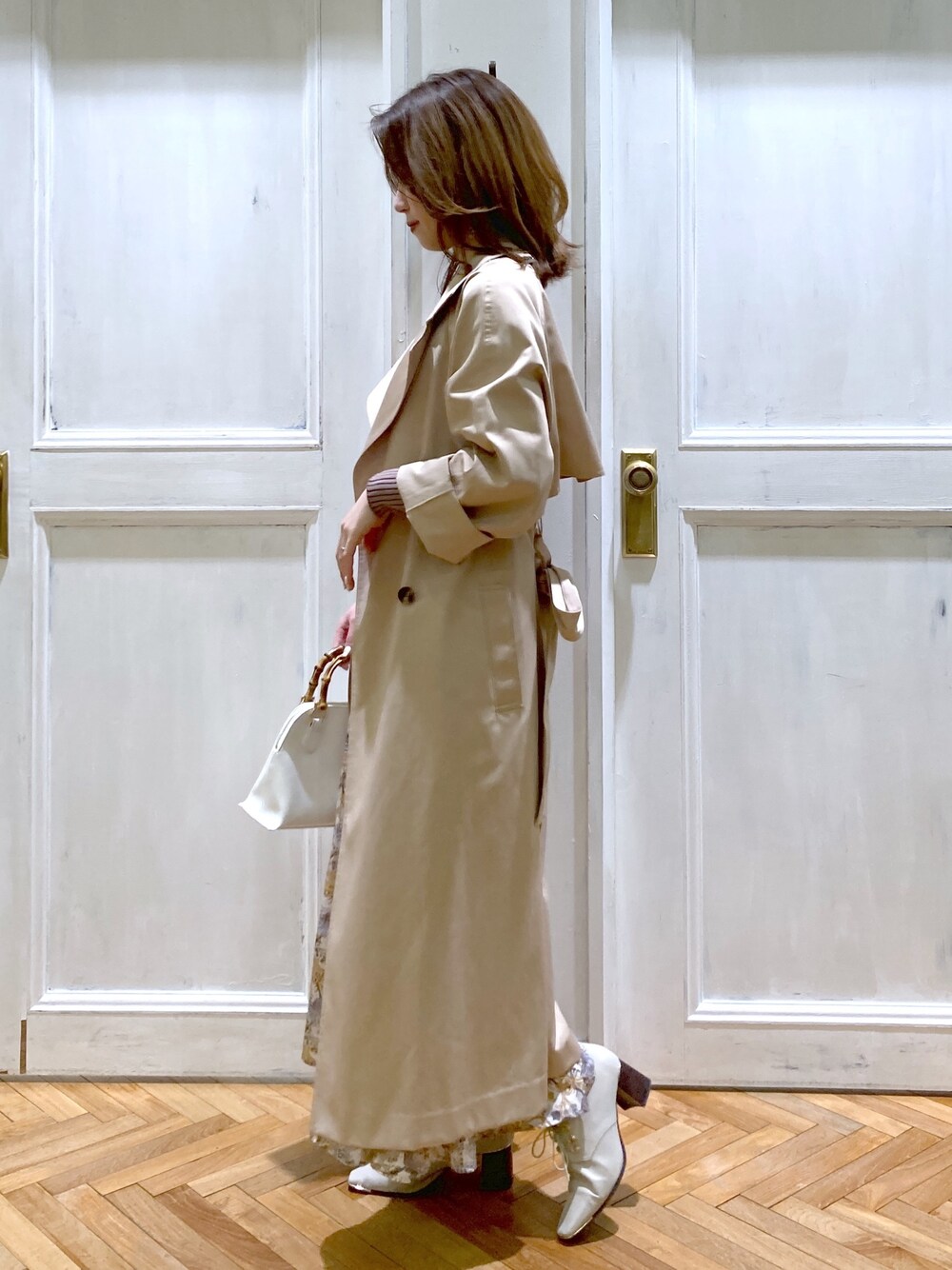 ベージュ系のトレンチコート、ベージュ系のニット/セーター、ホワイト系のスカートを着用したレディースの春コーディネートの3枚目の写真