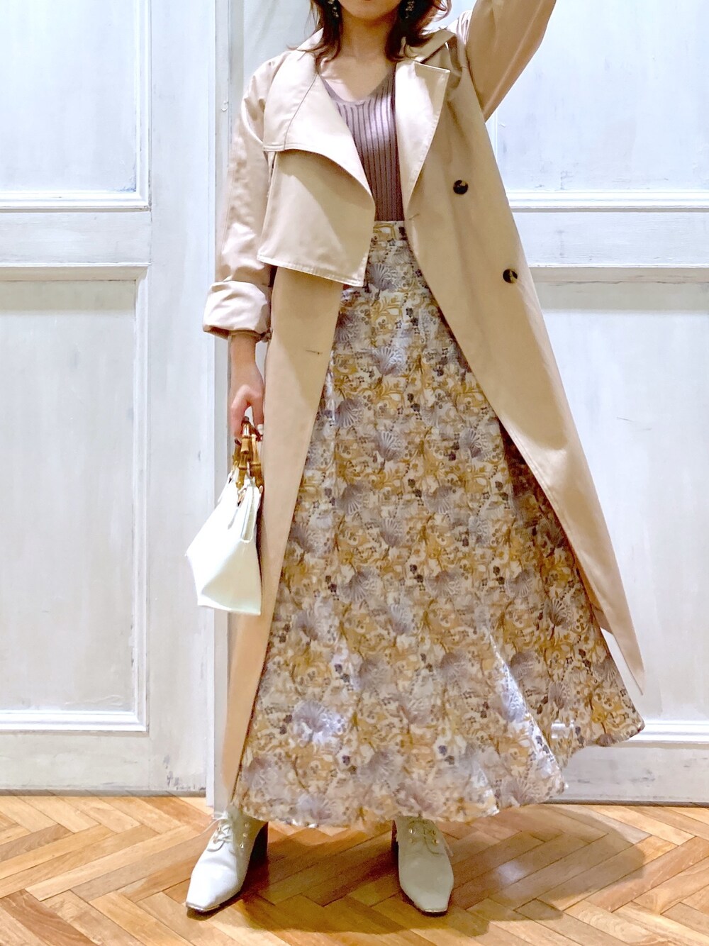 ベージュ系のトレンチコート、ベージュ系のニット/セーター、ホワイト系のスカートを着用したレディースの春コーディネートの2枚目の写真