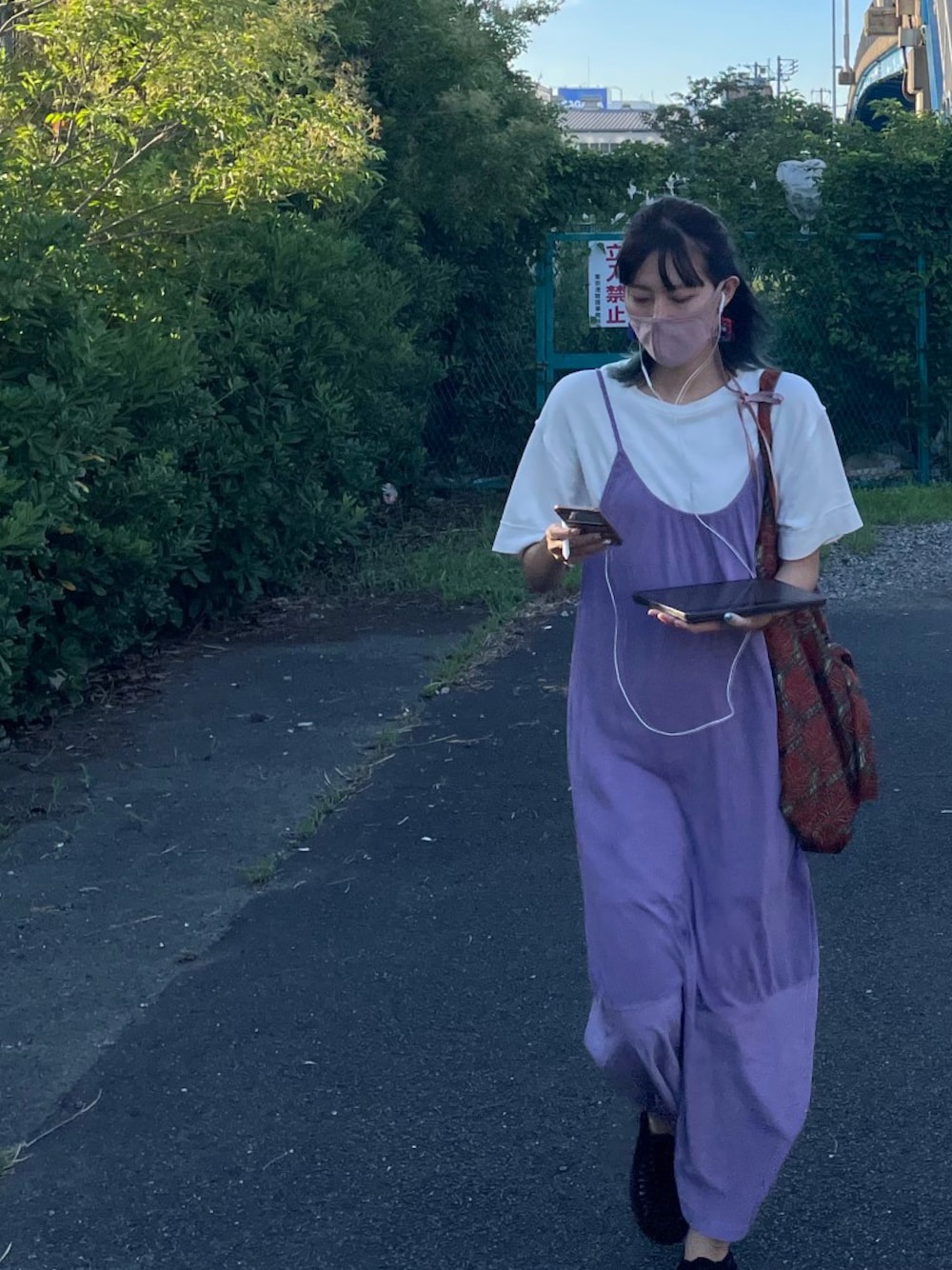 オレンジ系のハンドバッグ、パープル系のワンピース、ブラック系のサンダルを着用したレディースの冬コーディネートの1枚目の写真