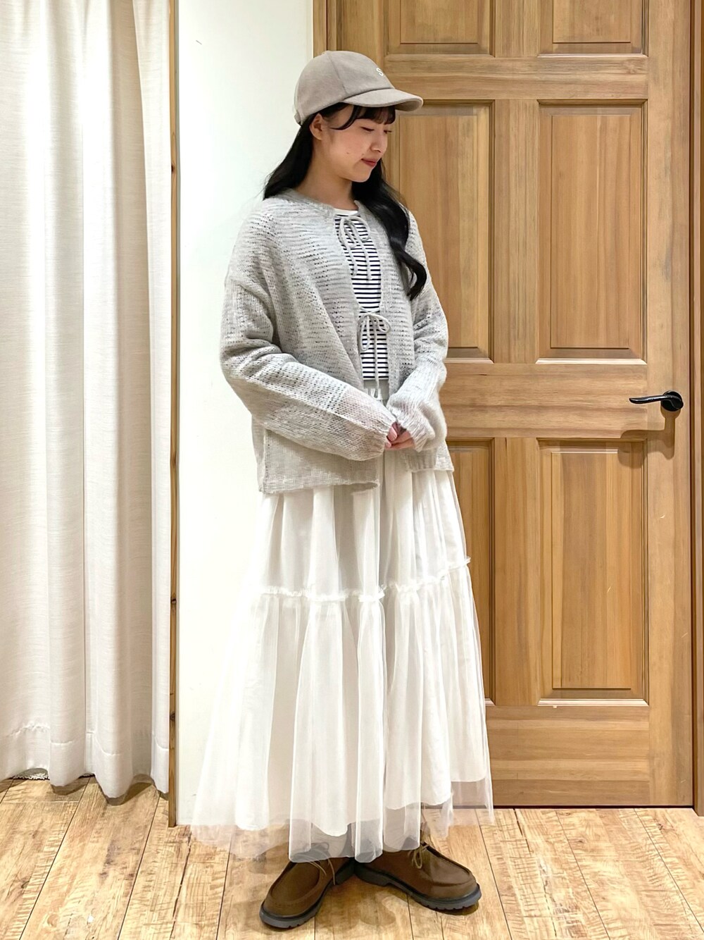 グレー系のカーディガン/ボレロ、ホワイト系のTシャツ/カットソー、ホワイト系のスカートを着用したレディースの冬コーディネートの1枚目の写真