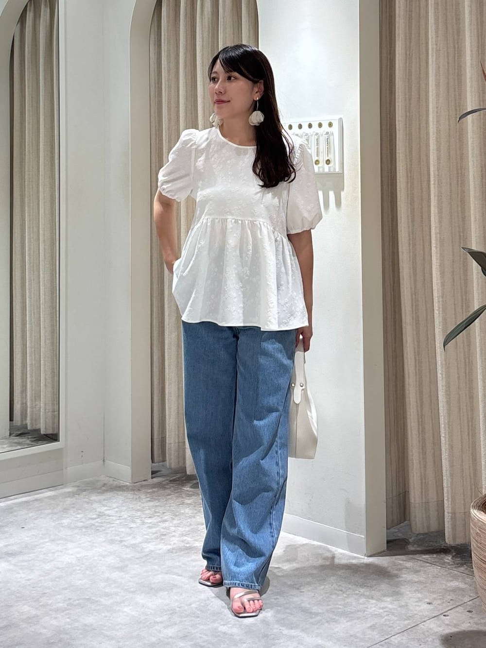 ブルー系のデニムパンツ、シルバー系のサンダル、ホワイト系のショルダーバッグを着用したレディースの夏コーディネートの1枚目の写真