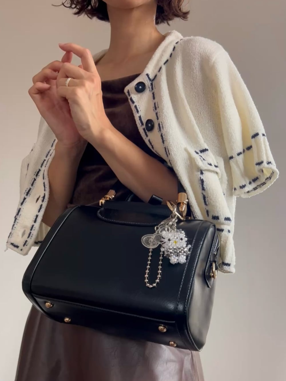 ブラック系のボストンバッグ、ブラウン系のスカートを着用したレディースの夏コーディネートの1枚目の写真