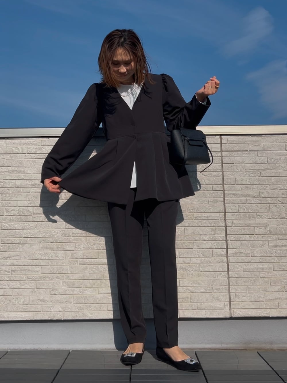 ブラック系のスーツセット、ブラック系のパンプスを着用したレディースの冬コーディネートの1枚目の写真