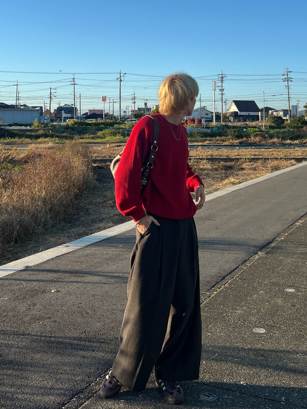 レッド系のニット/セーター、グレー系のスラックス、ブラウン系のスニーカーを着用したメンズの秋コーディネートの1枚目の写真