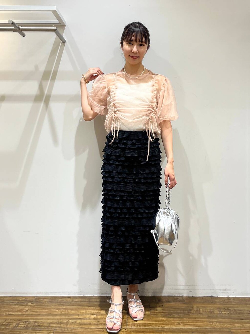 ブラック系のスカート、シルバー系のショルダーバッグ、シルバー系のサンダルを着用したレディースの春コーディネートの1枚目の写真