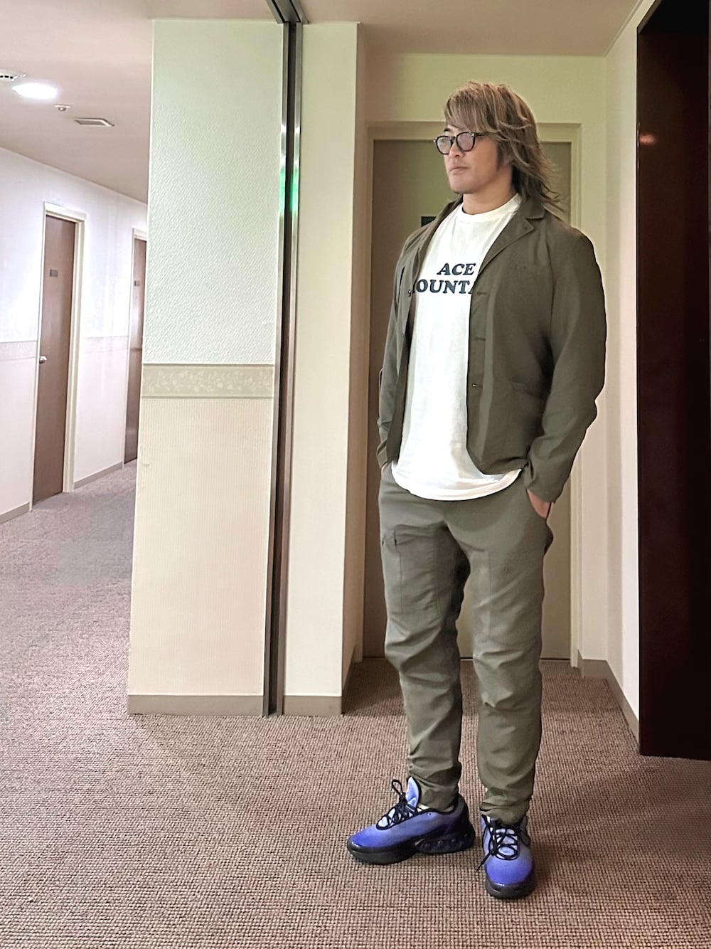 ホワイト系のTシャツ/カットソー、グリーン系のセットアップ、ブルー系のスニーカーを着用したメンズの冬コーディネートの1枚目の写真