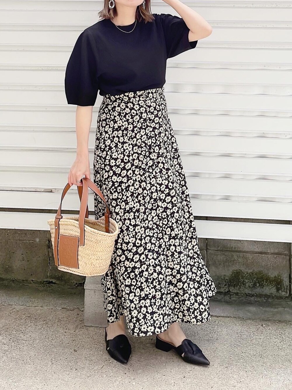 ブラック系のニット/セーター、ブラック系のスカート、ベージュ系のかごバッグを着用したレディースの春コーディネートの1枚目の写真