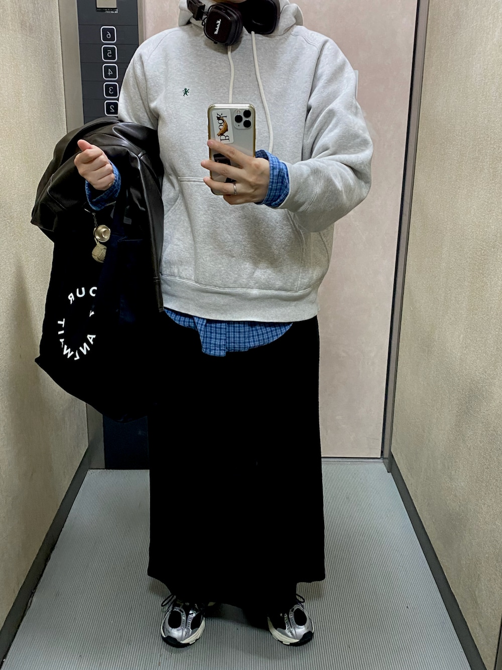 グレー系のパーカー、ブルー系のシャツ/ブラウス、ブラック系のスカートを着用したレディースの秋コーディネートの1枚目の写真