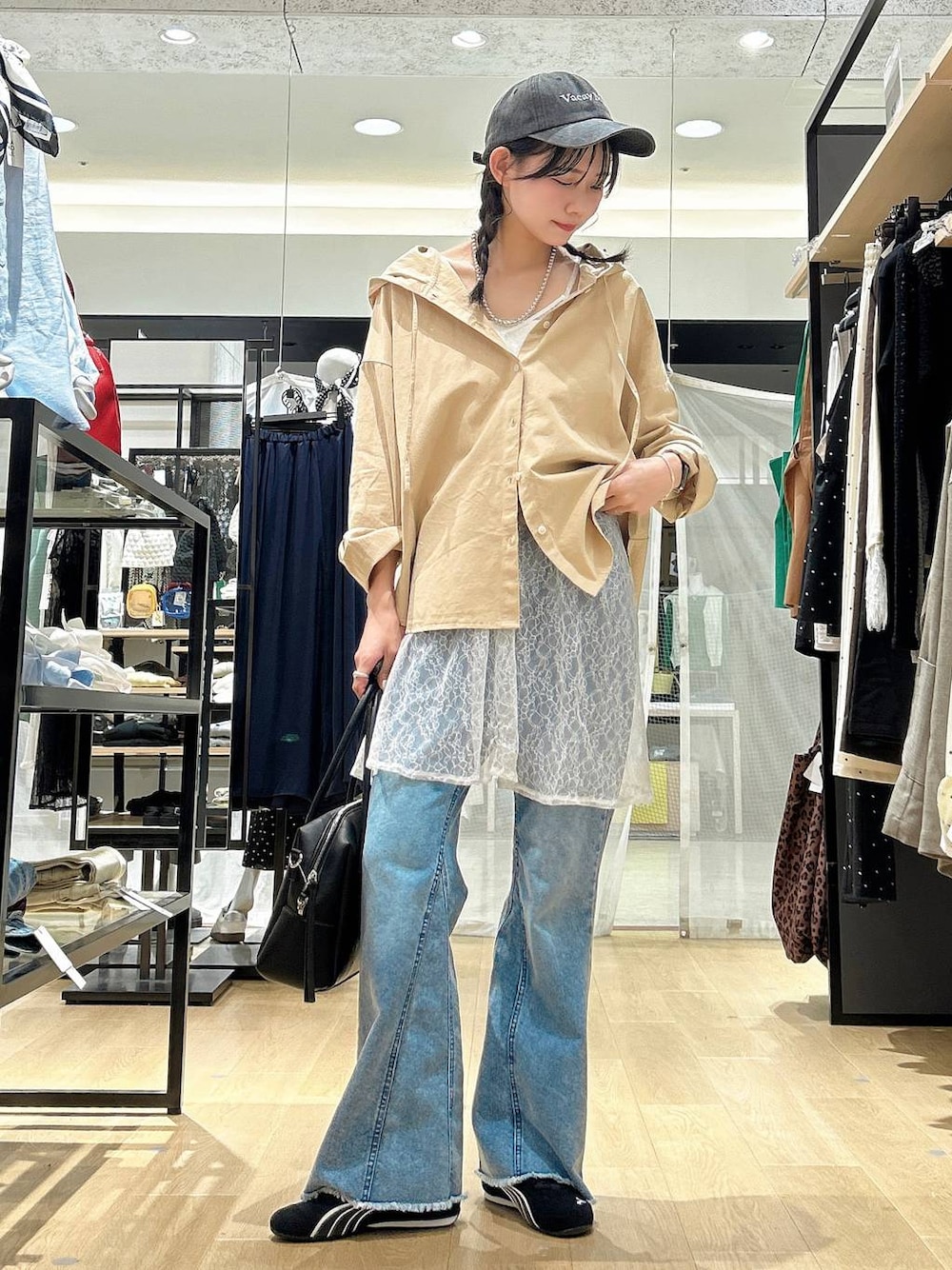 ブラック系のボストンバッグ、ブラック系のスニーカー、ブルー系のデニムパンツを着用したレディースの春コーディネートの1枚目の写真