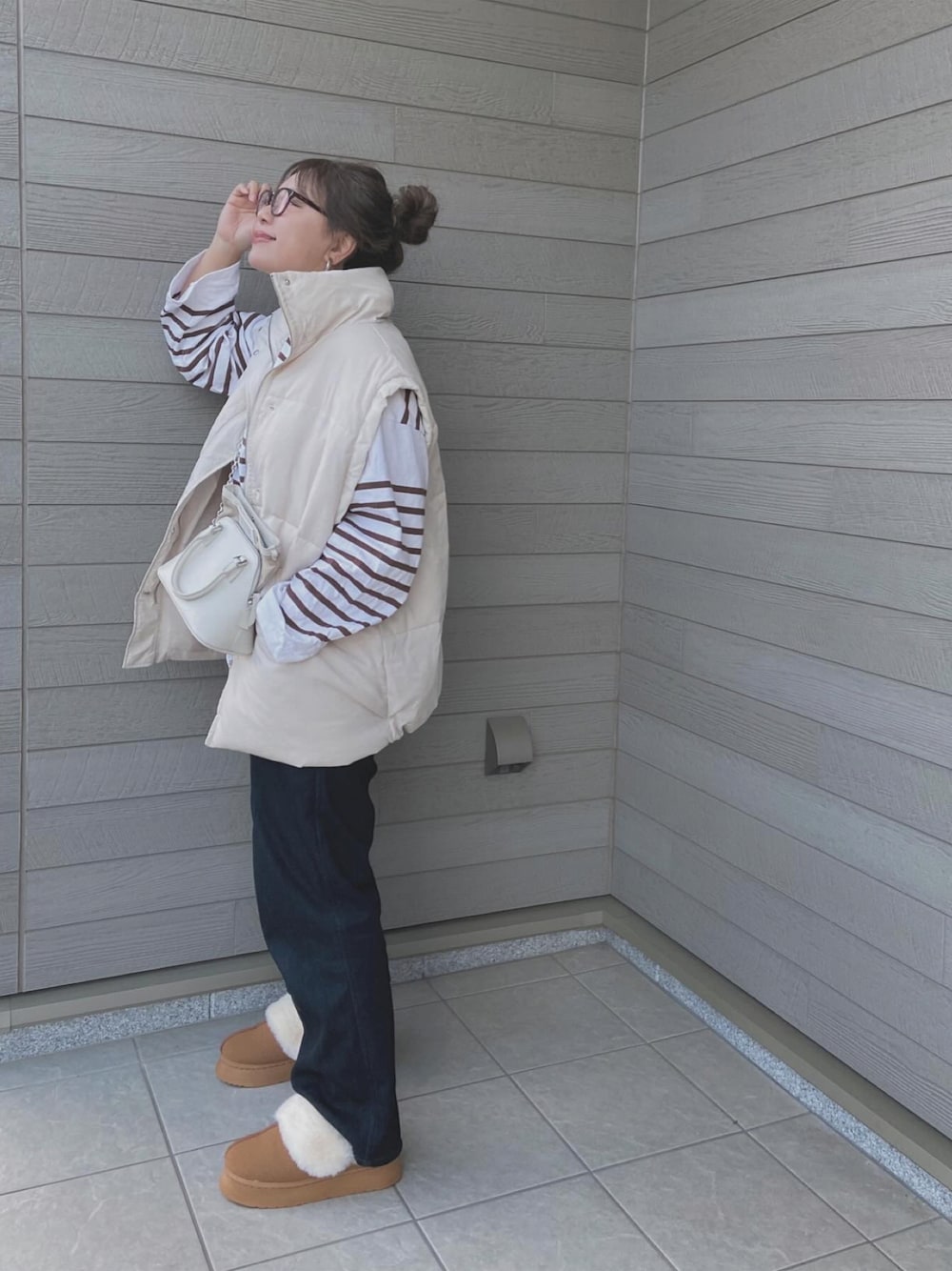 ホワイト系のダウンベスト、ブラウン系のTシャツ/カットソー、ホワイト系のショルダーバッグを着用したレディースの秋コーディネートの1枚目の写真