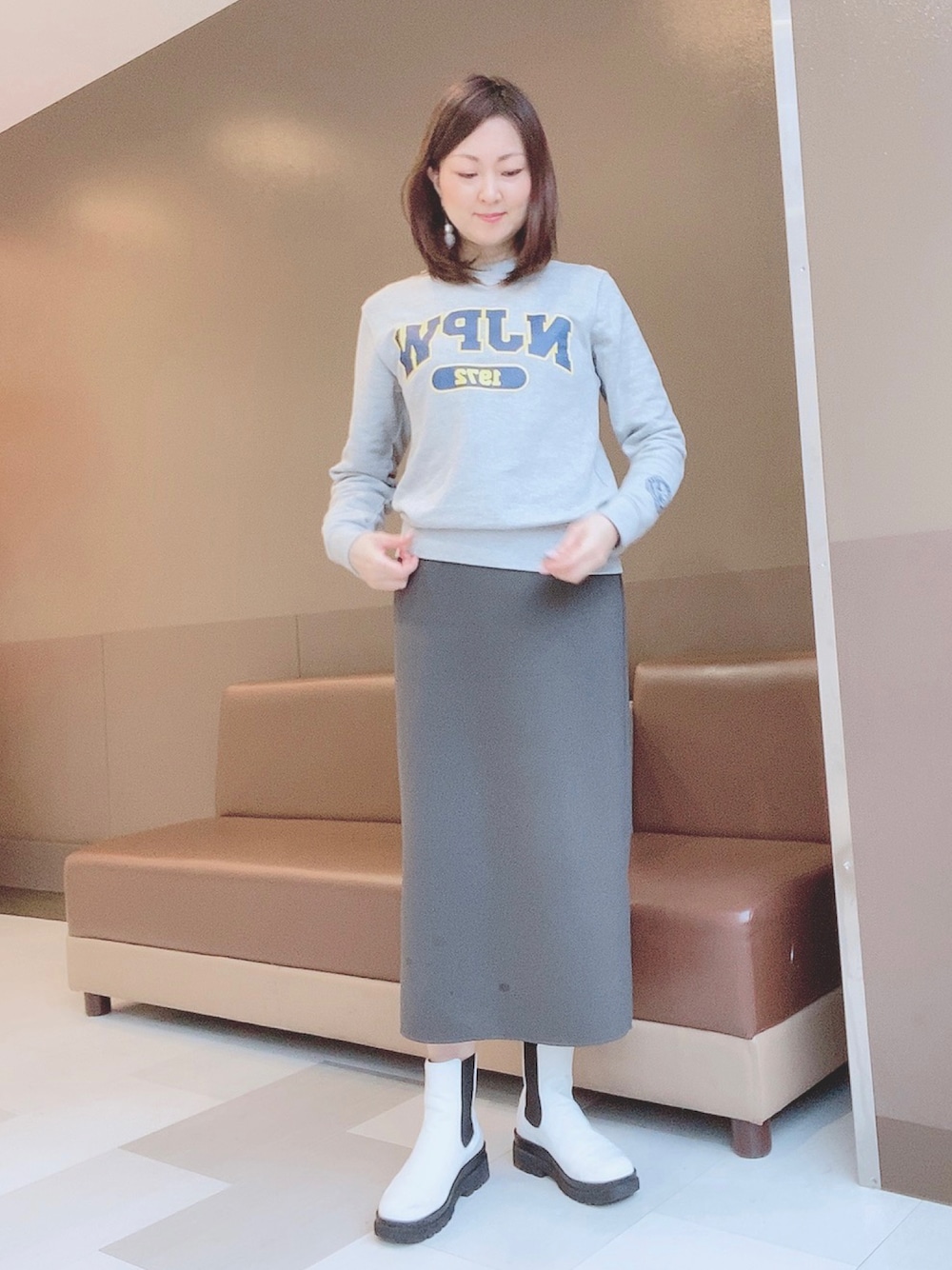グレー系のスカート、ホワイト系のレインシューズ、グレー系のスウェットを着用したレディースの春コーディネートの1枚目の写真