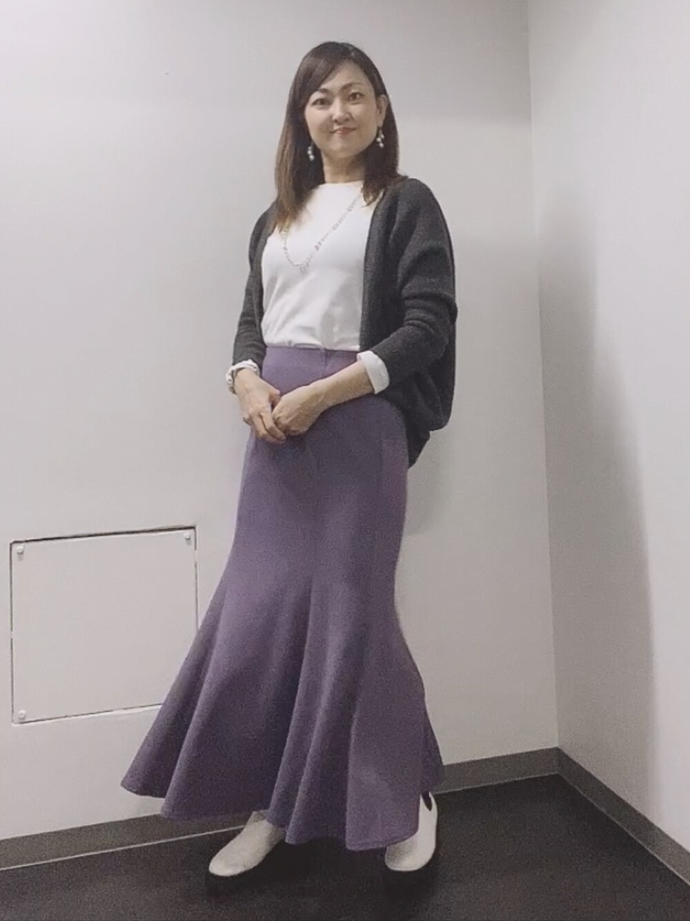 ホワイト系のTシャツ/カットソー、グレー系のカーディガン/ボレロ、パープル系のスカートを着用したレディースの秋コーディネートの1枚目の写真