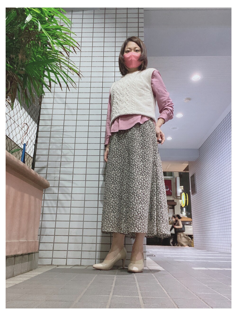ピンク系のシャツ/ブラウス、ホワイト系のベスト、ブラック系のスカートを着用したレディースの秋コーディネートの1枚目の写真