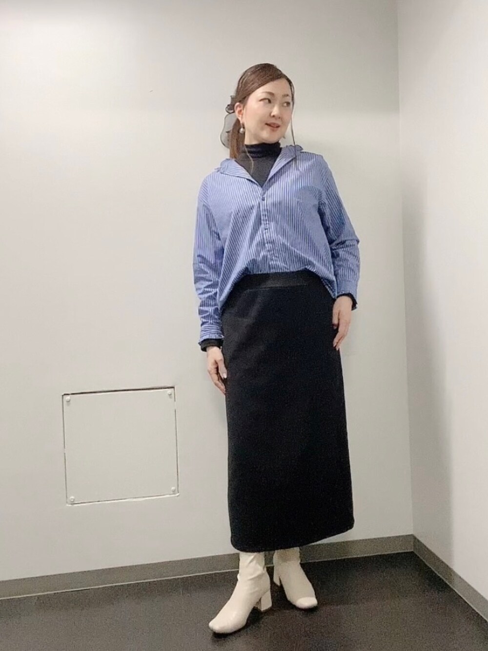 ブラック系のスカート、ホワイト系のブーツ、ブルー系のシャツ/ブラウスを着用したレディースの冬コーディネートの1枚目の写真