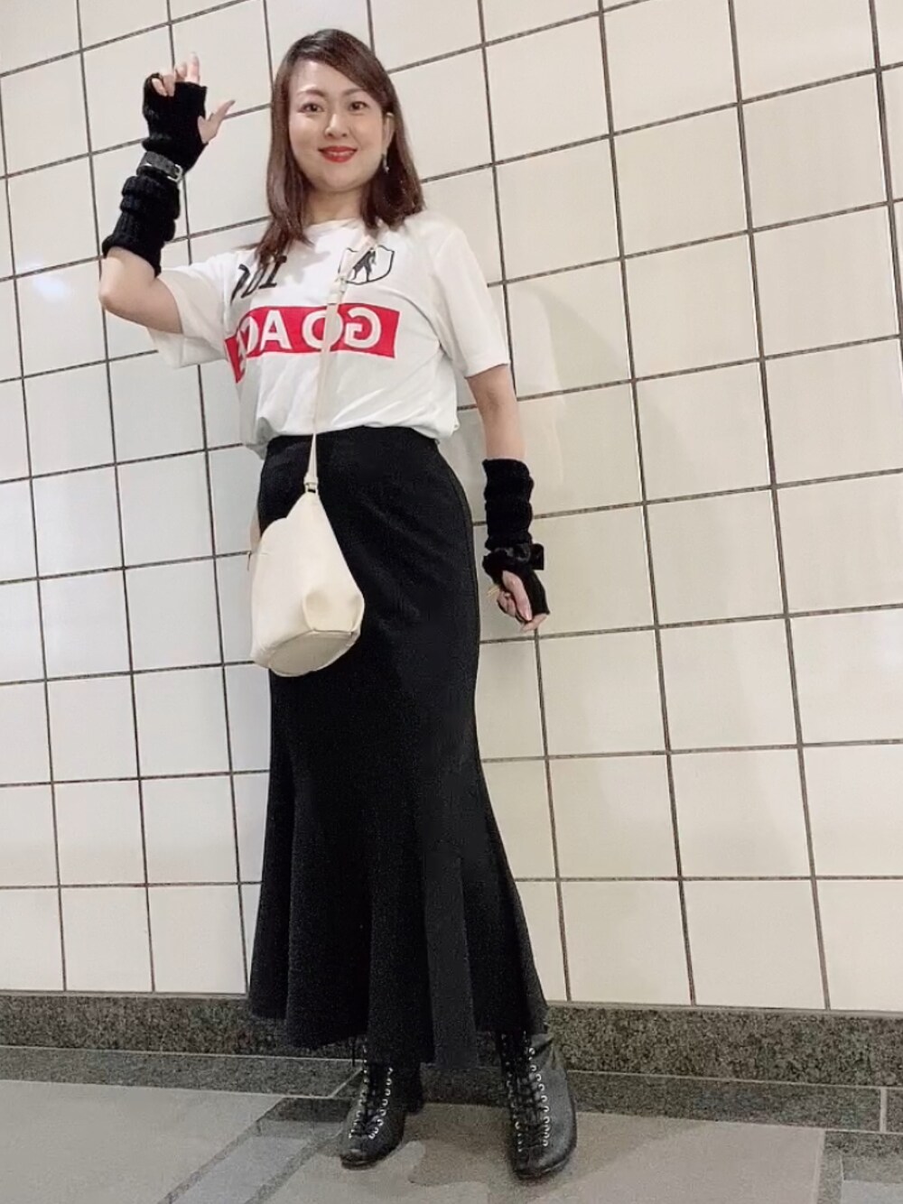 ホワイト系のTシャツ/カットソー、ブラック系のスカート、ホワイト系のショルダーバッグを着用したレディースの秋コーディネートの1枚目の写真