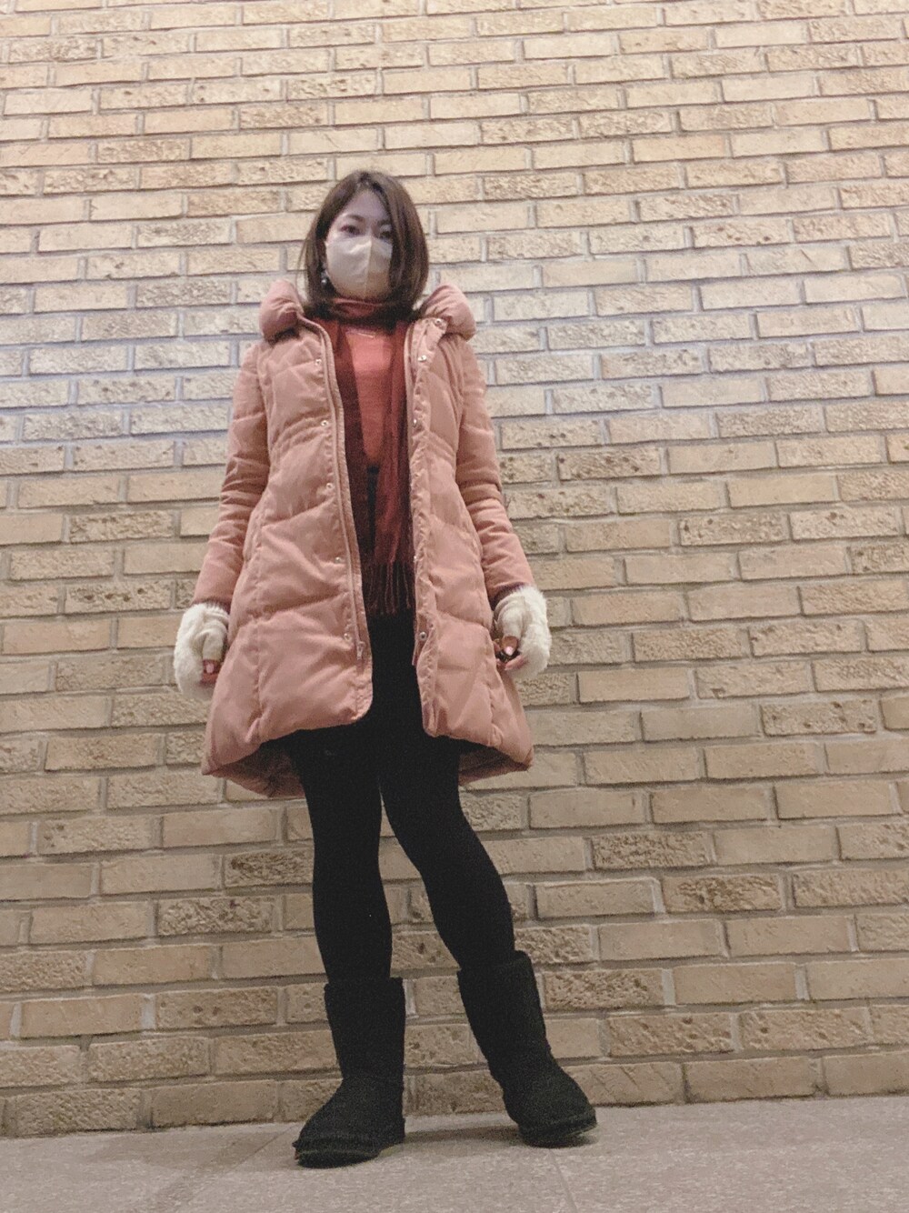 ピンク系のダウンジャケット/コート、ピンク系のTシャツ/カットソー、ブルー系のスカートを着用したレディースの冬コーディネートの1枚目の写真