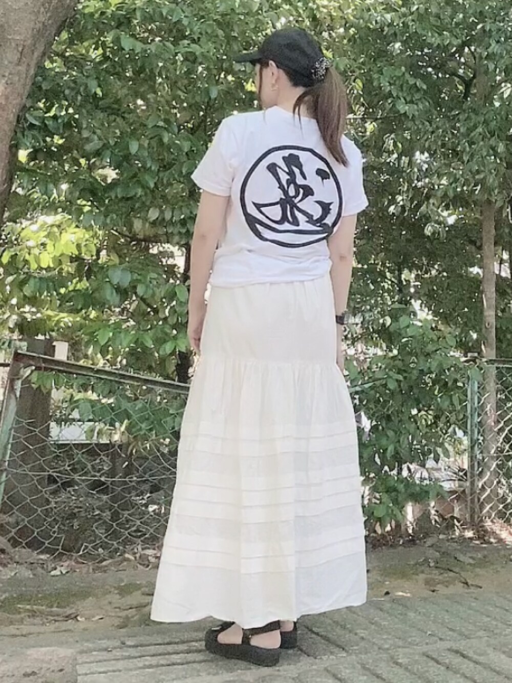 ホワイト系のTシャツ/カットソー、ホワイト系のスカート、ブラック系のサンダルを着用したレディースの夏コーディネートの1枚目の写真