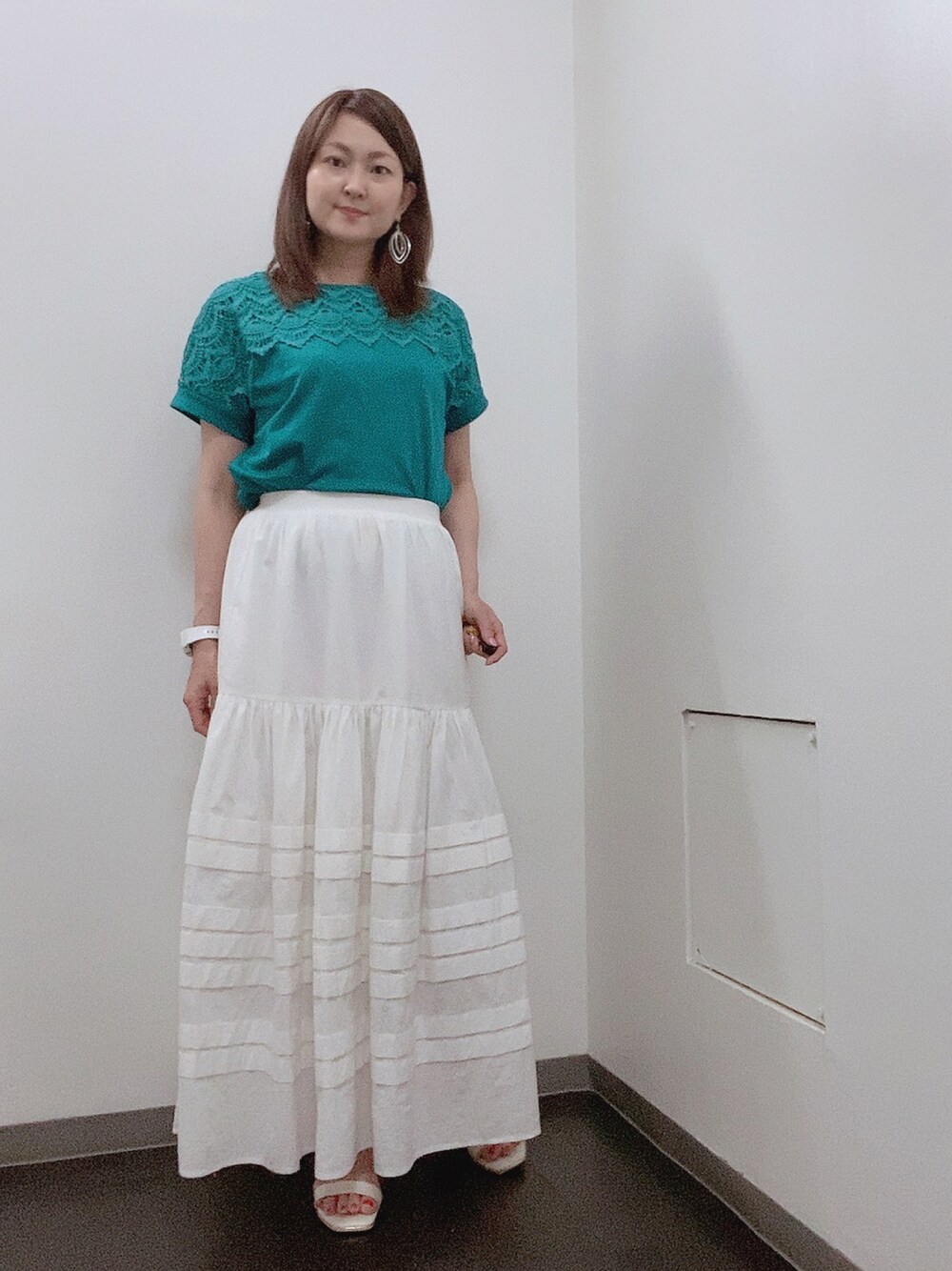ホワイト系のスカート、ホワイト系のサンダル、グリーン系のTシャツ/カットソーを着用したレディースの夏コーディネートの1枚目の写真