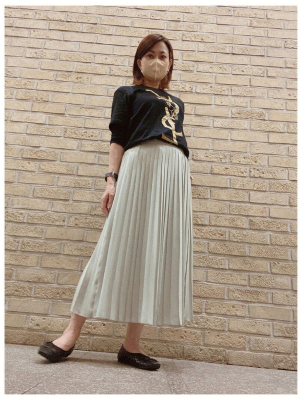 ブラック系のTシャツ/カットソー、グリーン系のスカート、ブラック系のパンプスを着用したレディースの秋コーディネートの1枚目の写真