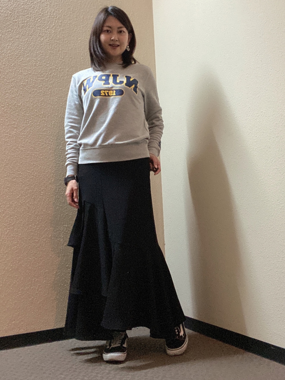 ブラック系のスカート、グレー系のスウェット、ブラック系のスニーカーを着用したレディースの春コーディネートの1枚目の写真