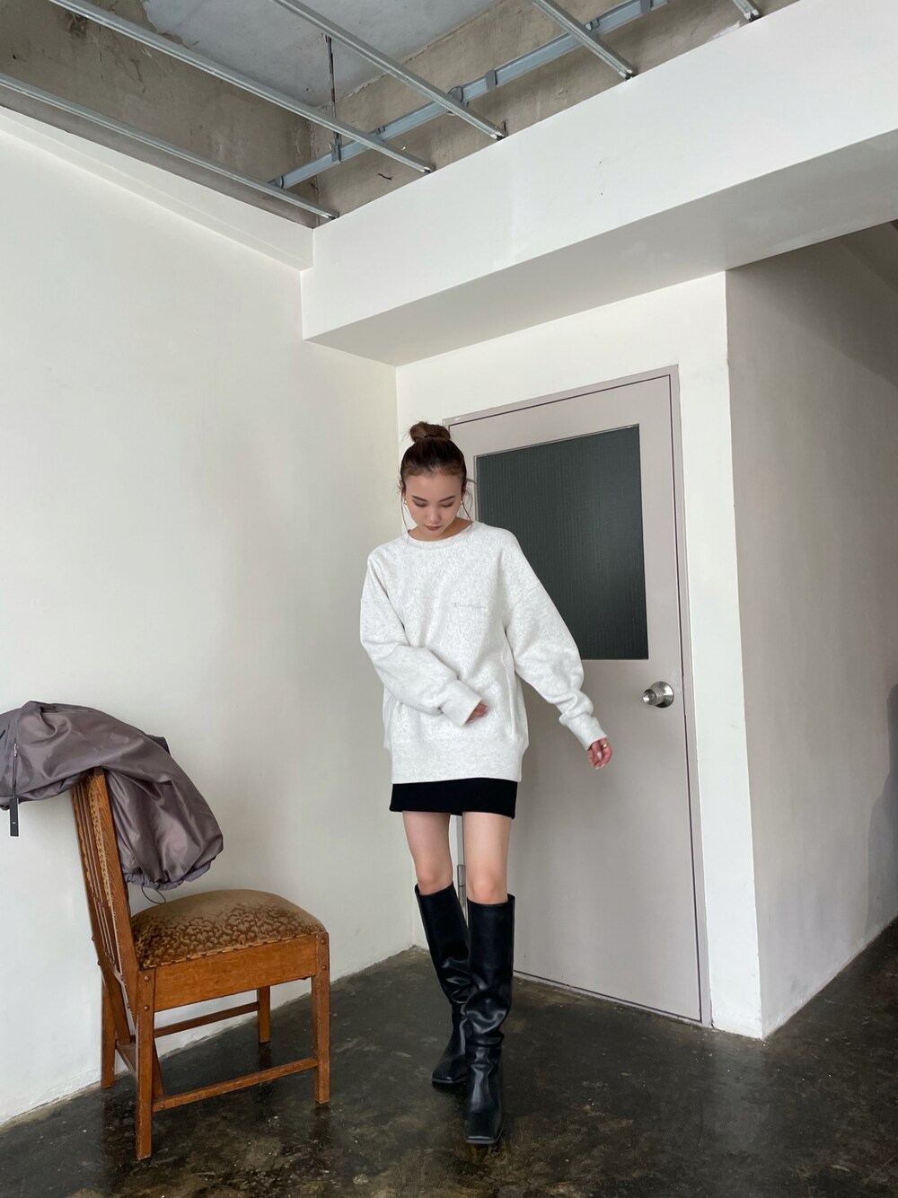 グレー系のトップス、ブラック系のブーツを着用したレディースの秋コーディネートの1枚目の写真