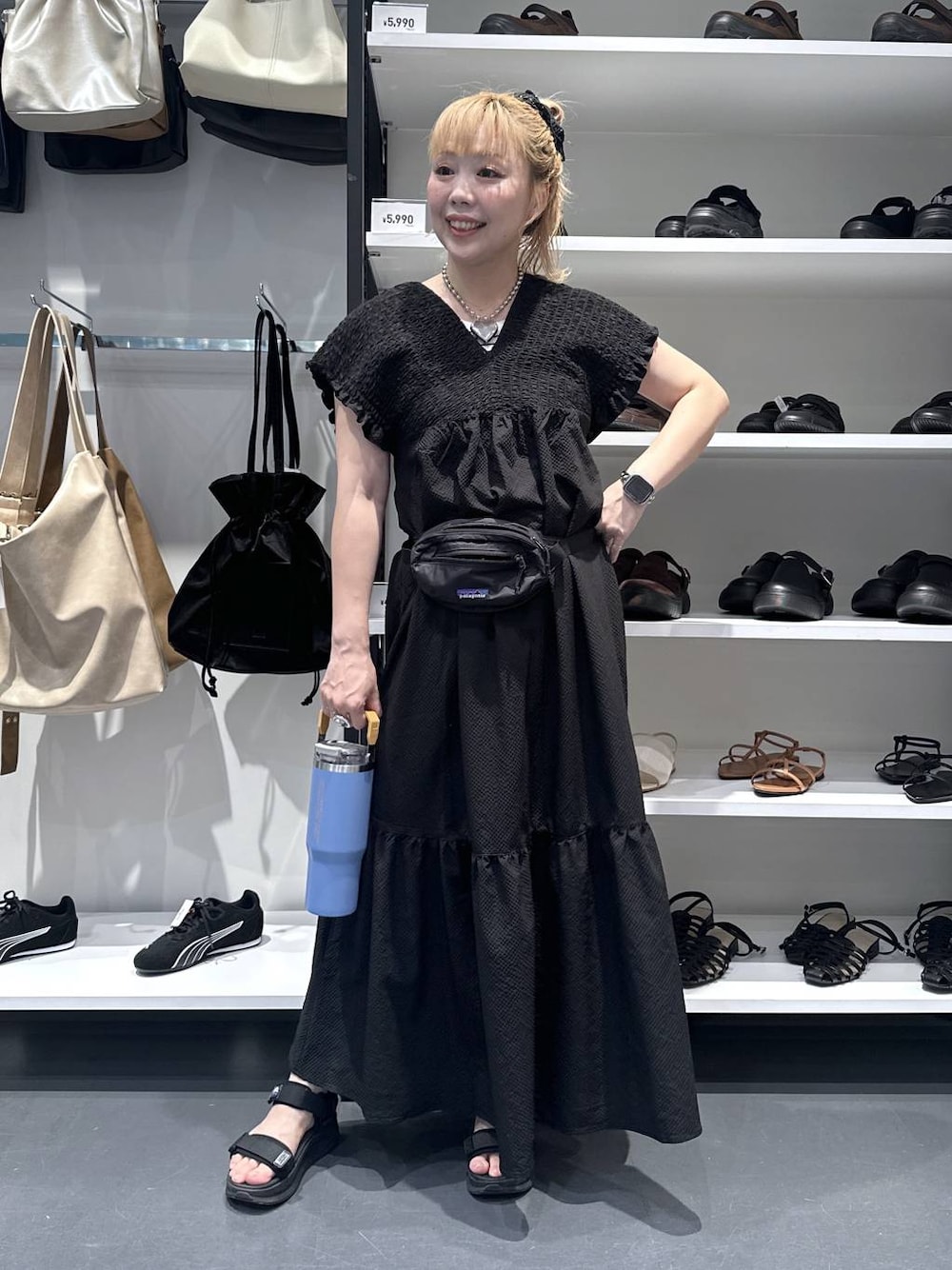 ブラック系のワンピース、シルバー系のデジタル腕時計、オレンジ系の水筒を着用したレディースの夏コーディネートの1枚目の写真