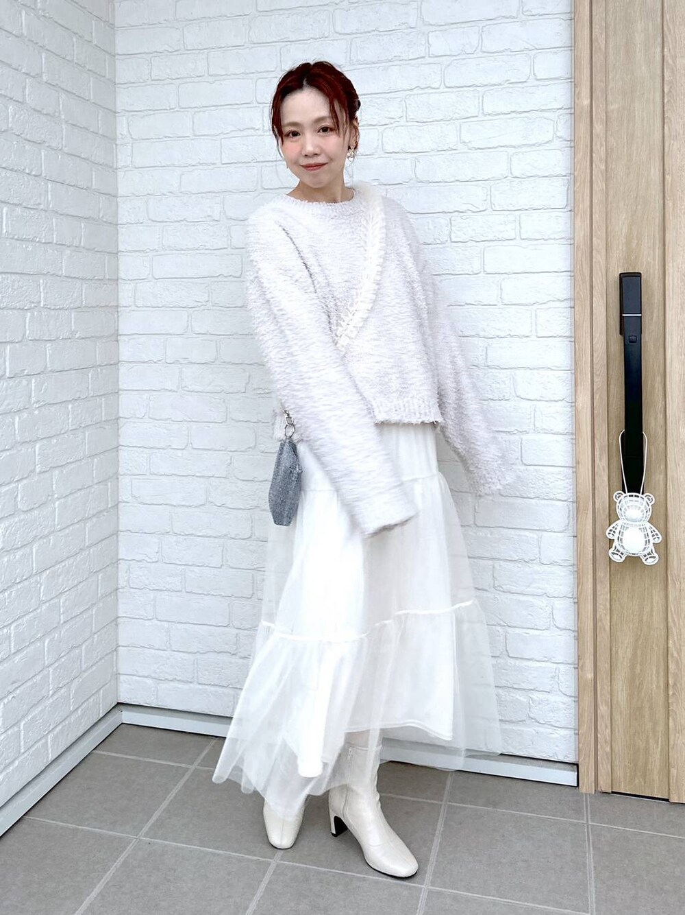 グレー系のニット/セーター、ホワイト系のブーツ、ホワイト系のTシャツ/カットソーを着用したレディースの冬コーディネートの1枚目の写真