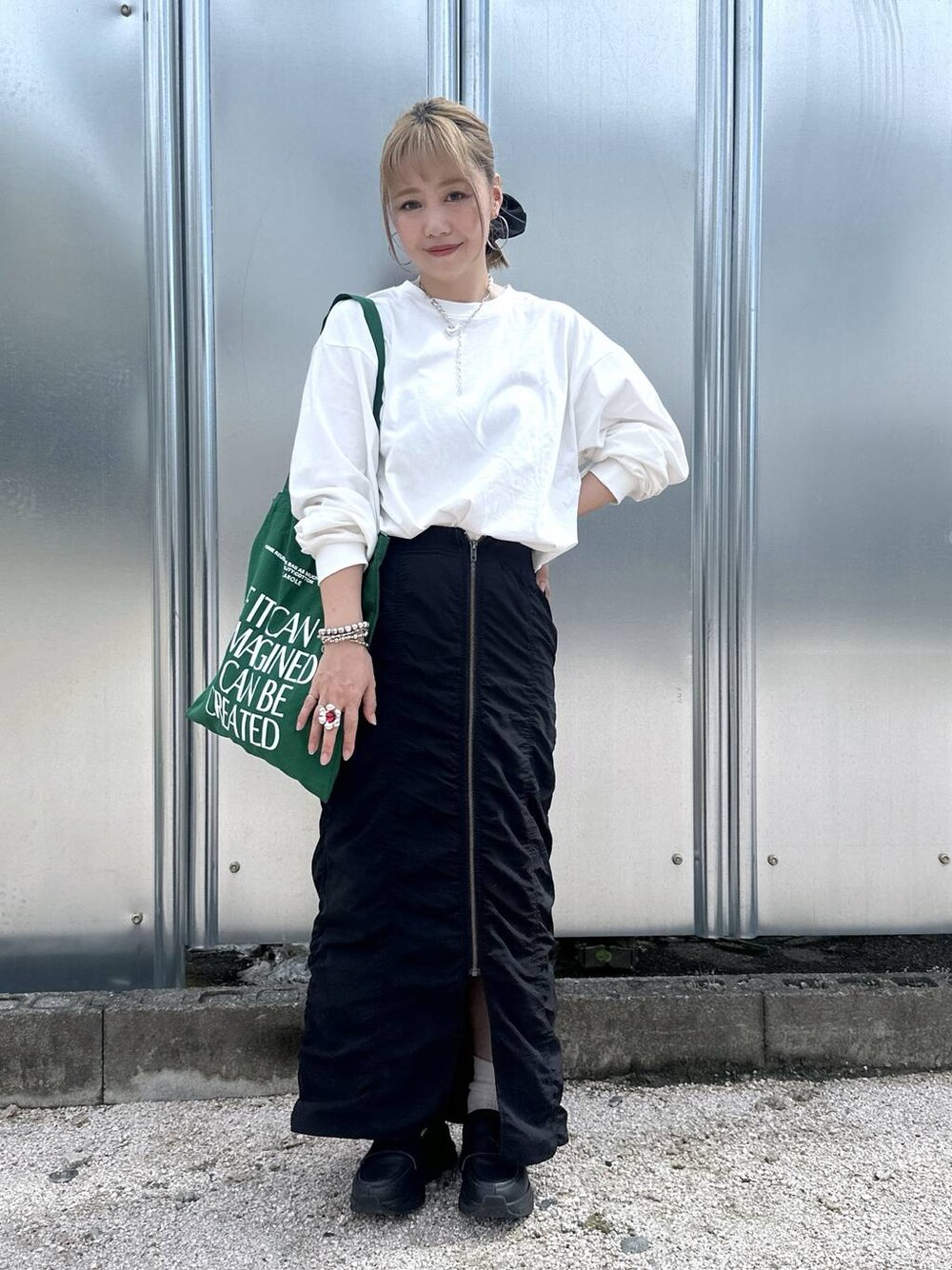 ブラック系のスカート、グリーン系のトートバッグ、その他のピアス(両耳用)を着用したレディースの秋コーディネートの1枚目の写真