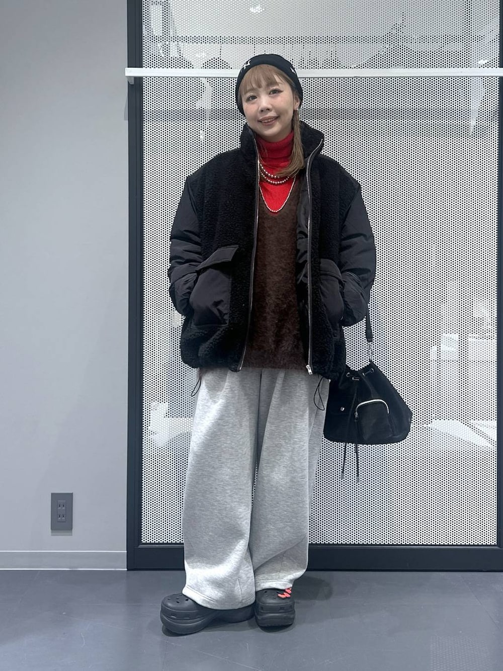 ブラック系のブルゾン、ブラック系のショルダーバッグ、ブラウン系のベストを着用したレディースの冬コーディネートの1枚目の写真