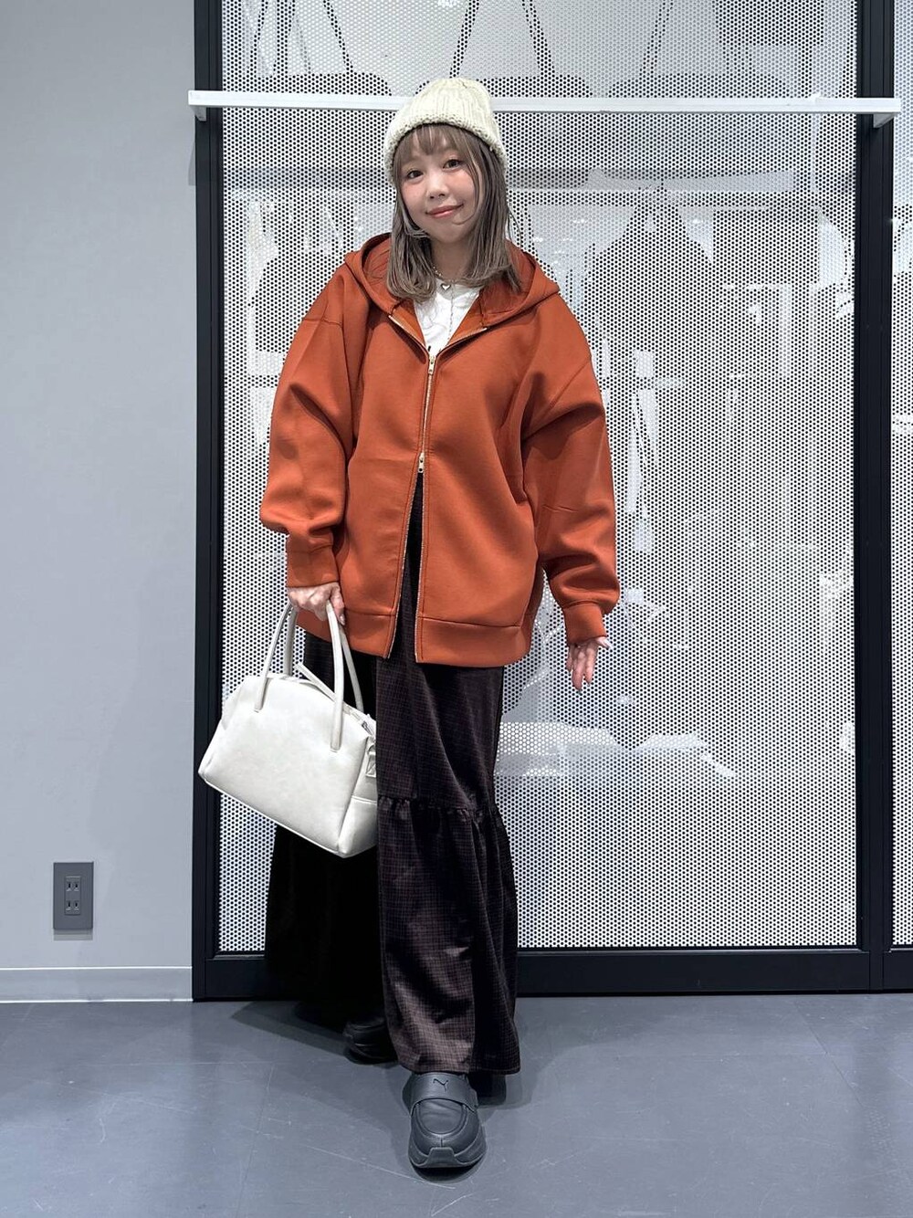 グレー系のボストンバッグ、ブラウン系のパーカー、ホワイト系のTシャツ/カットソーを着用したレディースの秋コーディネートの1枚目の写真