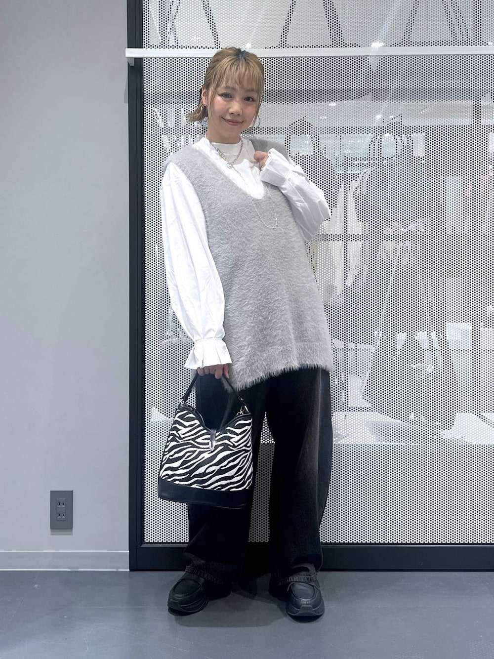 ブラック系のデニムパンツ、その他のショルダーバッグ、グレー系のベストを着用したレディースの秋コーディネートの1枚目の写真