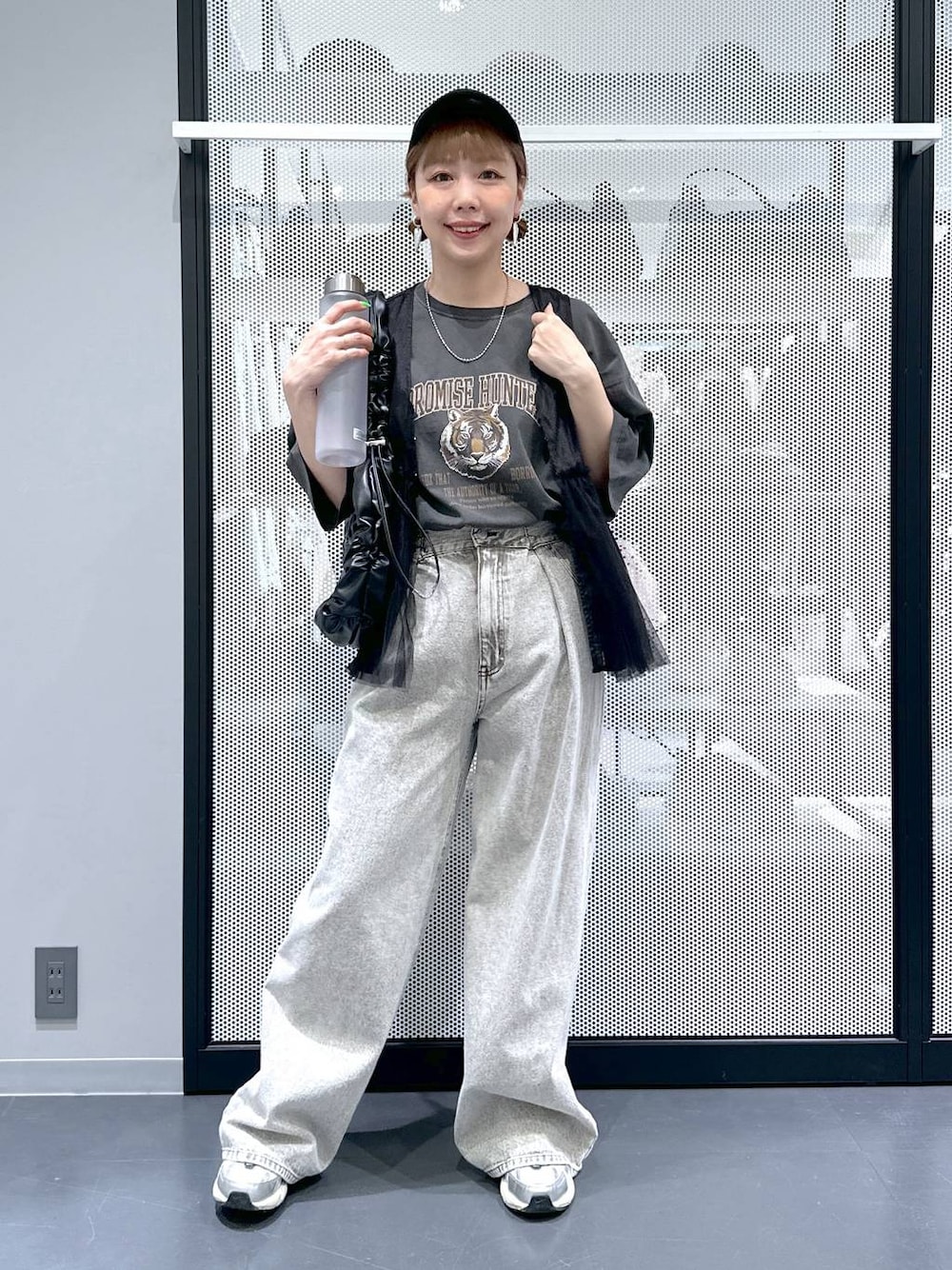 グレー系のデニムパンツ、ブラック系のベスト、グレー系のTシャツ/カットソーを着用したレディースの春コーディネートの1枚目の写真