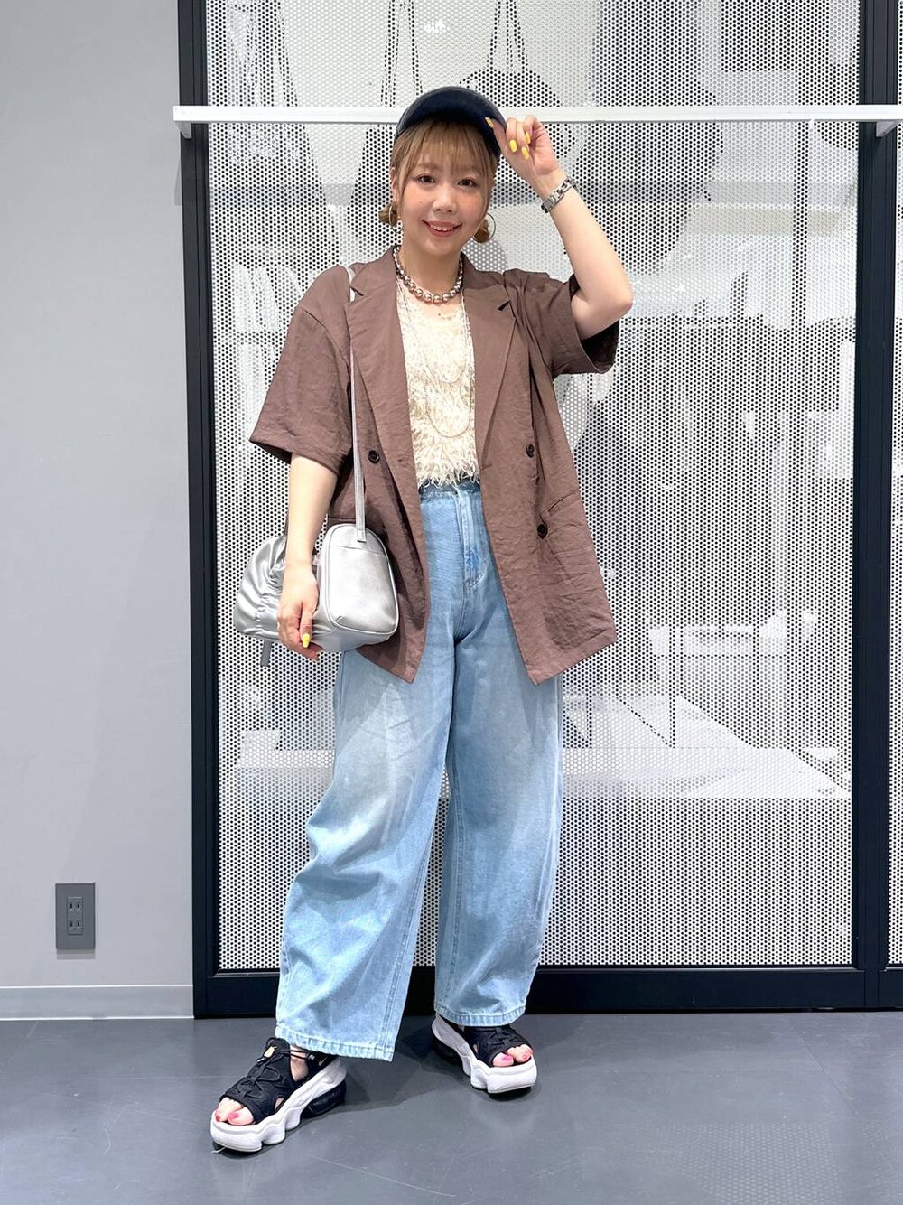 ブルー系のデニムパンツ、シルバー系のショルダーバッグ、ホワイト系のベストを着用したレディースの夏コーディネートの1枚目の写真