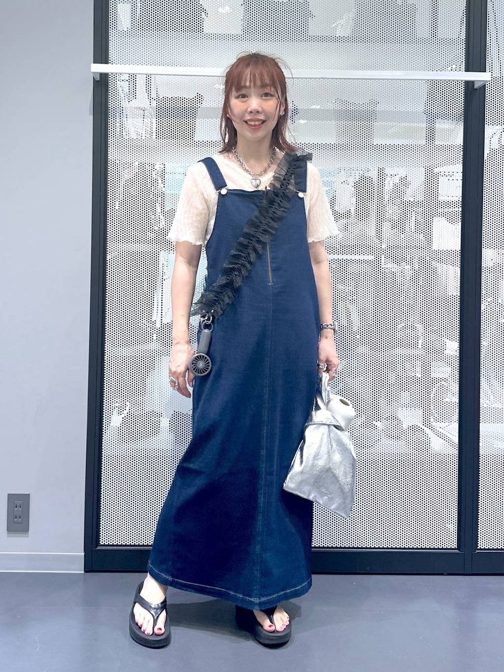 ブルー系のジャンパースカート、ブラック系のサンダル、ベージュ系のTシャツ/カットソーを着用したレディースの夏コーディネートの1枚目の写真