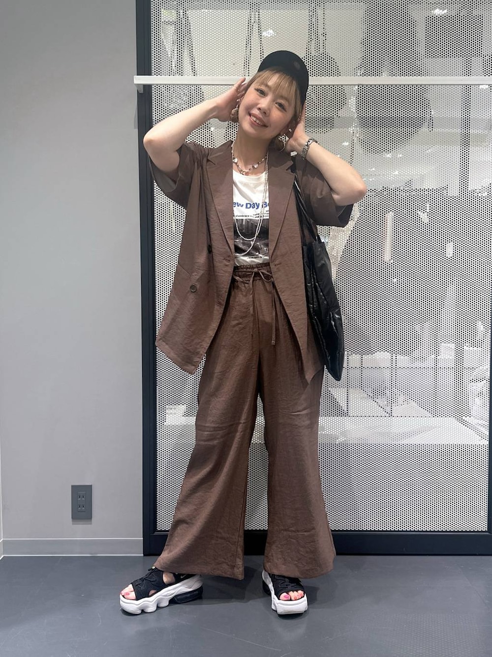 ブラック系のトートバッグ、ブラウン系のテーラードジャケット、ブラウン系のその他パンツを着用したレディースの春コーディネートの1枚目の写真