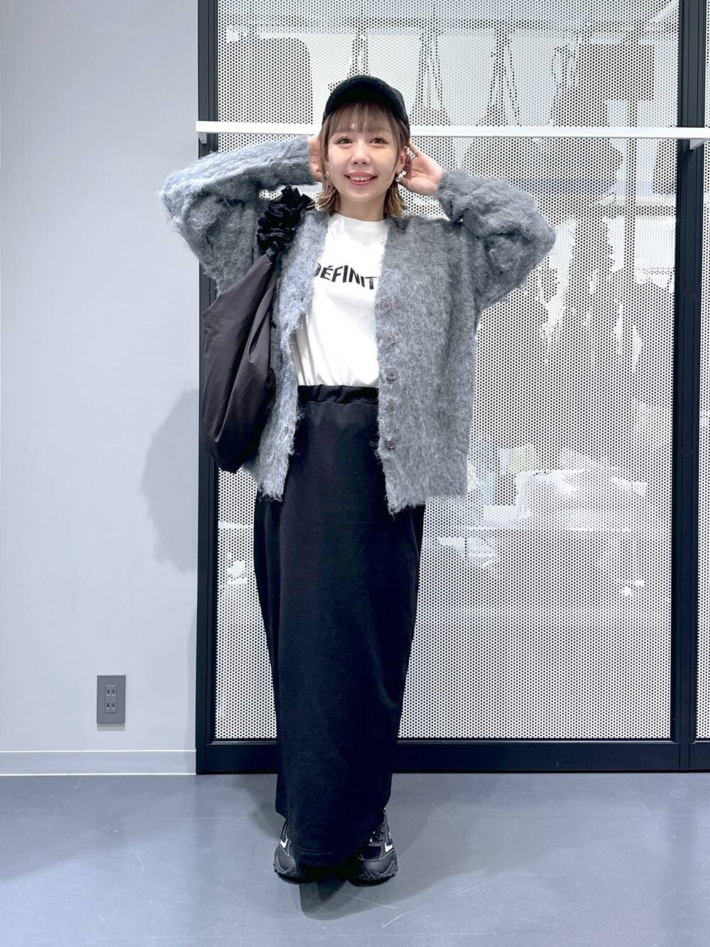 グレー系のスニーカー、グレー系のカーディガン/ボレロ、ブラック系のショルダーバッグを着用したレディースの冬コーディネートの1枚目の写真