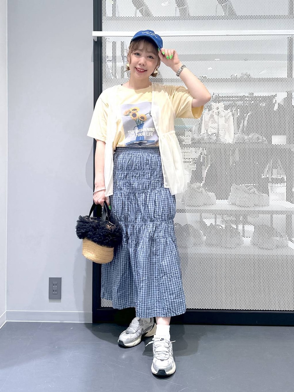 ベージュ系のショルダーバッグ、イエロー系のTシャツ/カットソー、ブルー系のスカートを着用したレディースの春コーディネートの1枚目の写真
