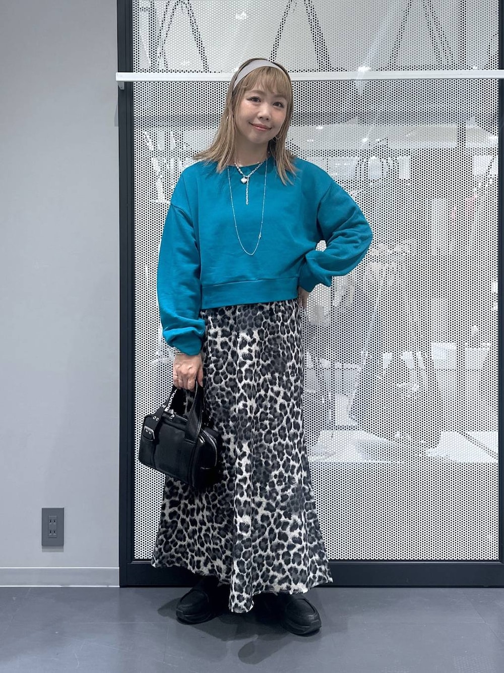 ブラック系のショルダーバッグ、グレー系のスカート、ブルー系のスウェットを着用したレディースの秋コーディネートの1枚目の写真