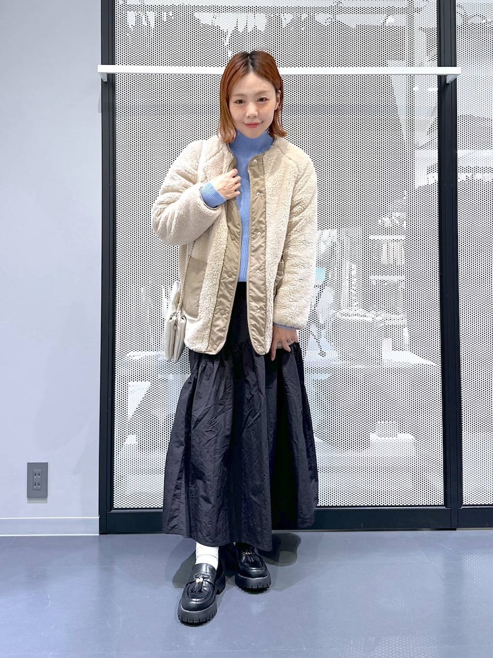 ホワイト系のショルダーバッグ、ブラック系のローファー、ベージュ系のブルゾンを着用したレディースの冬コーディネートの1枚目の写真