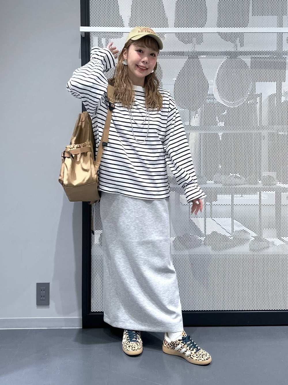 ベージュ系のその他シューズ、ベージュ系のバックパック/リュック、グレー系のスカートを着用したレディースの春コーディネートの1枚目の写真