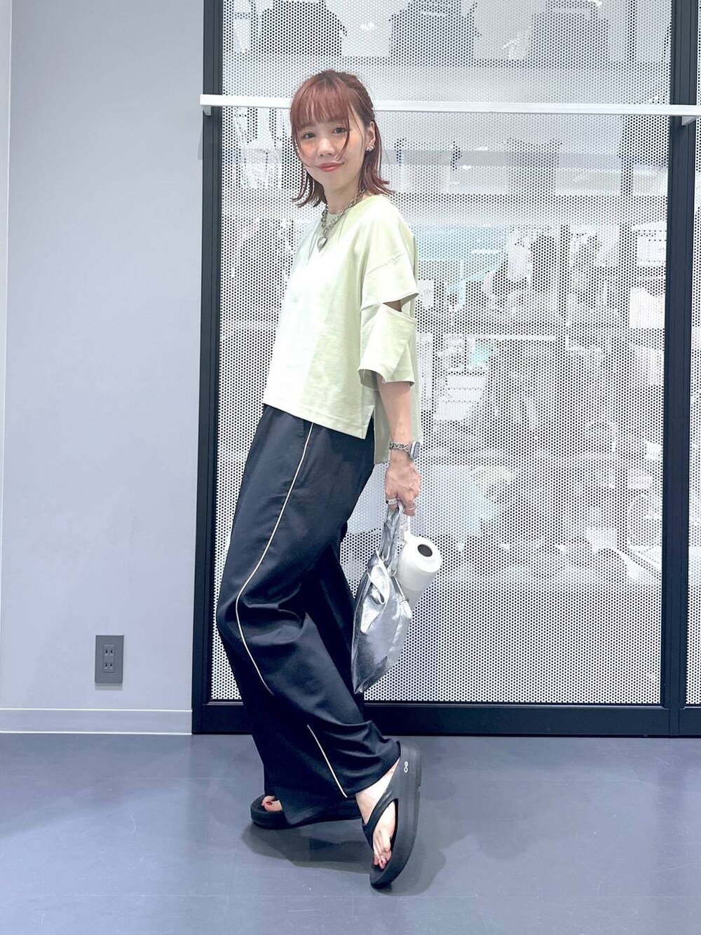 シルバー系のショルダーバッグ、グリーン系のTシャツ/カットソー、ブラック系のサンダルを着用したレディースの夏コーディネートの1枚目の写真