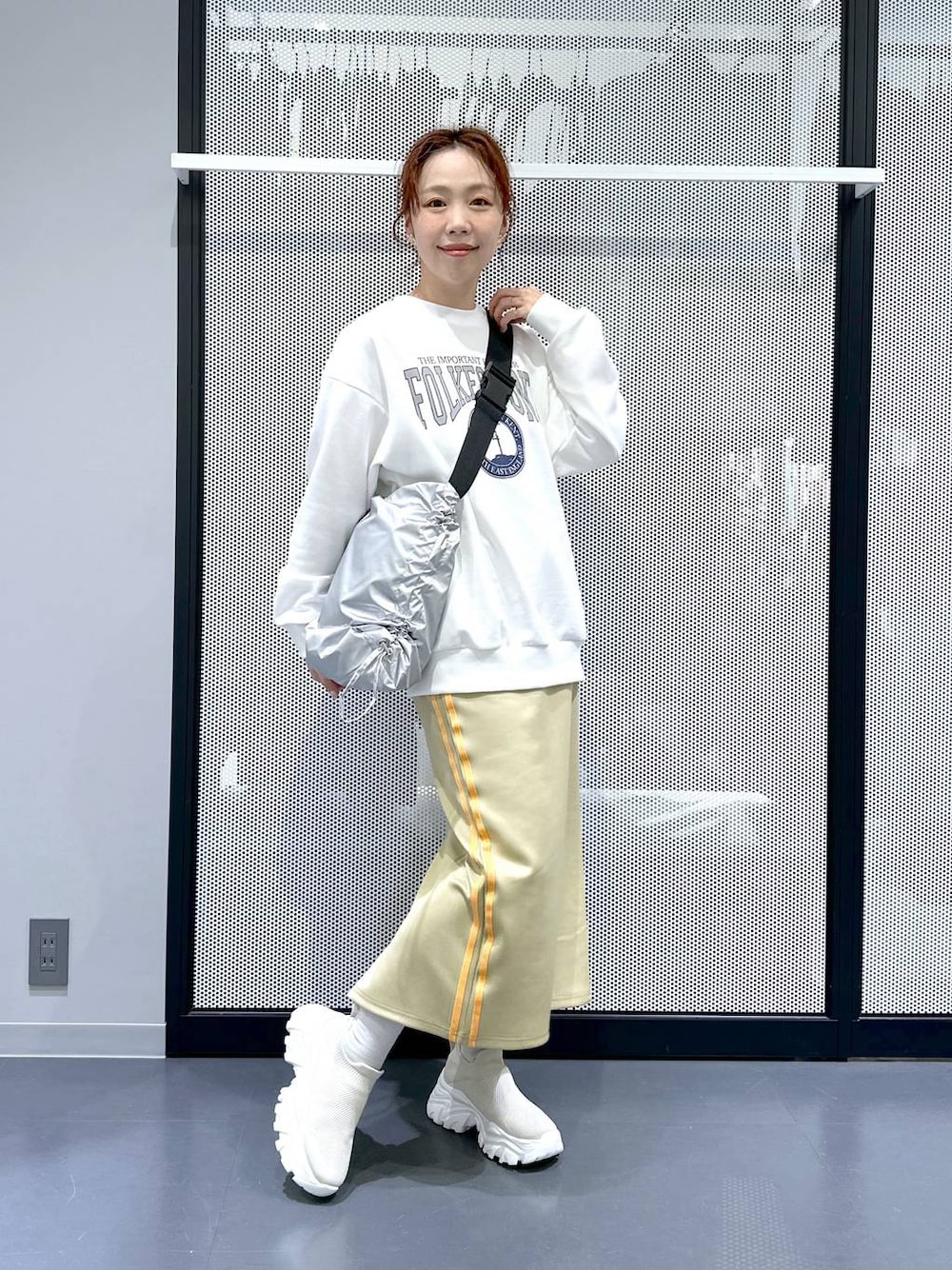 グリーン系のスカート、シルバー系のショルダーバッグ、ブラック系のシュシュを着用したレディースの冬コーディネートの1枚目の写真