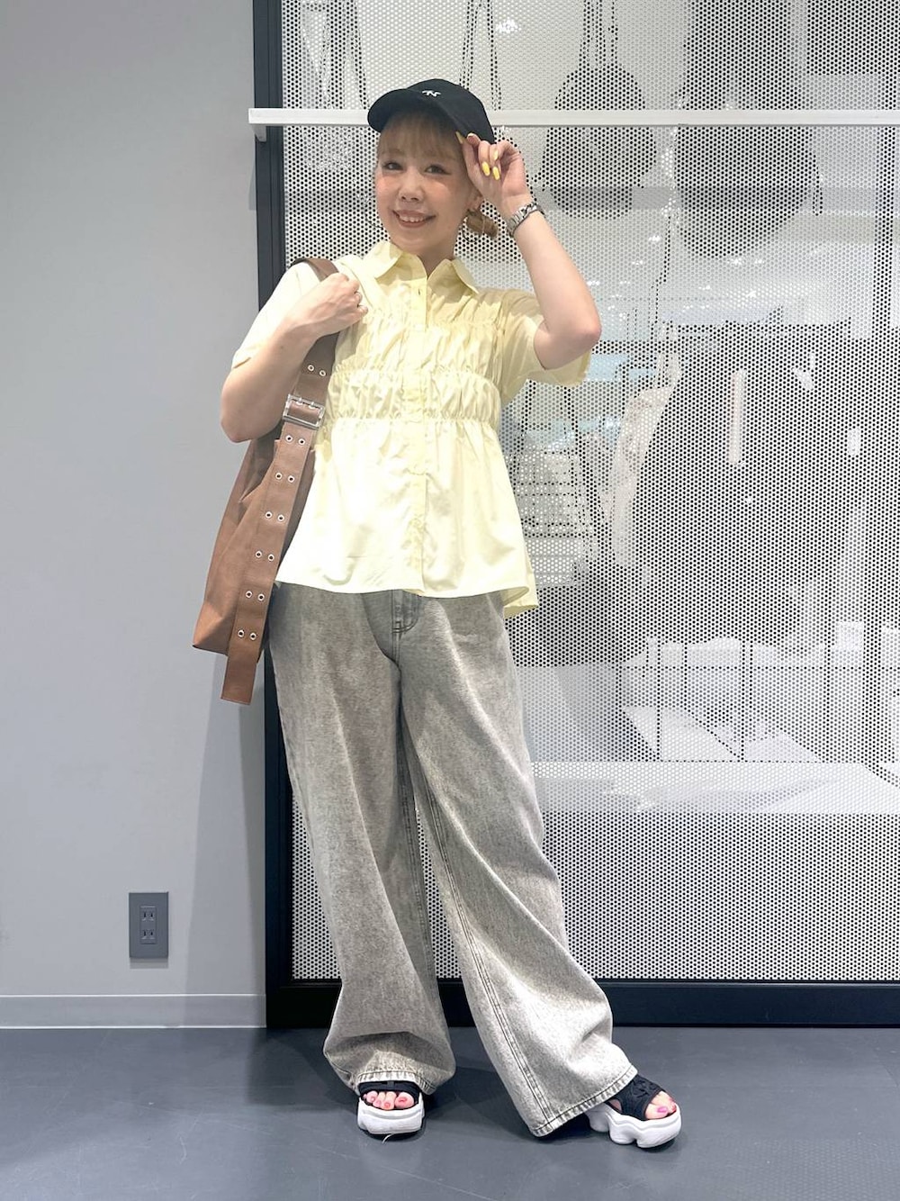 グレー系のデニムパンツ、ブラウン系のショルダーバッグ、イエロー系のシャツ/ブラウスを着用したレディースの夏コーディネートの1枚目の写真