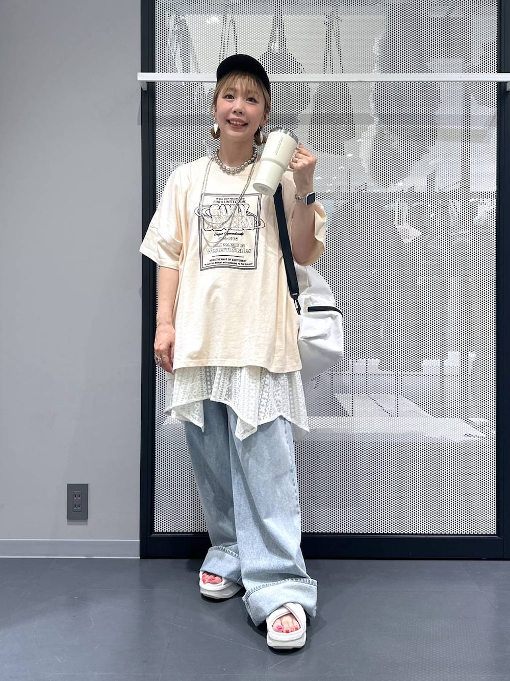 ホワイト系のショルダーバッグ、ブルー系のデニムパンツ、ベージュ系のワンピースを着用したレディースの夏コーディネートの1枚目の写真