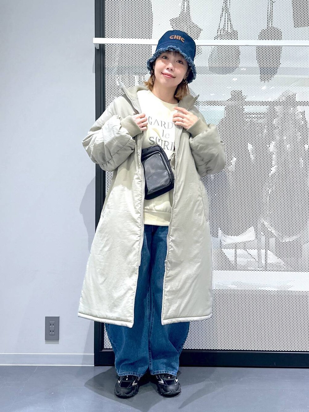 グレー系のスニーカー、ブルー系のデニムパンツ、グリーン系のミリタリージャケットを着用したレディースの冬コーディネートの1枚目の写真