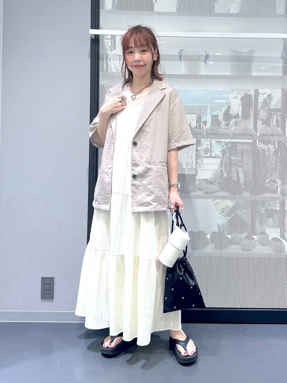 ブラック系のショルダーバッグ、ベージュ系のワンピース、ベージュ系のTシャツ/カットソーを着用したレディースの夏コーディネートの1枚目の写真