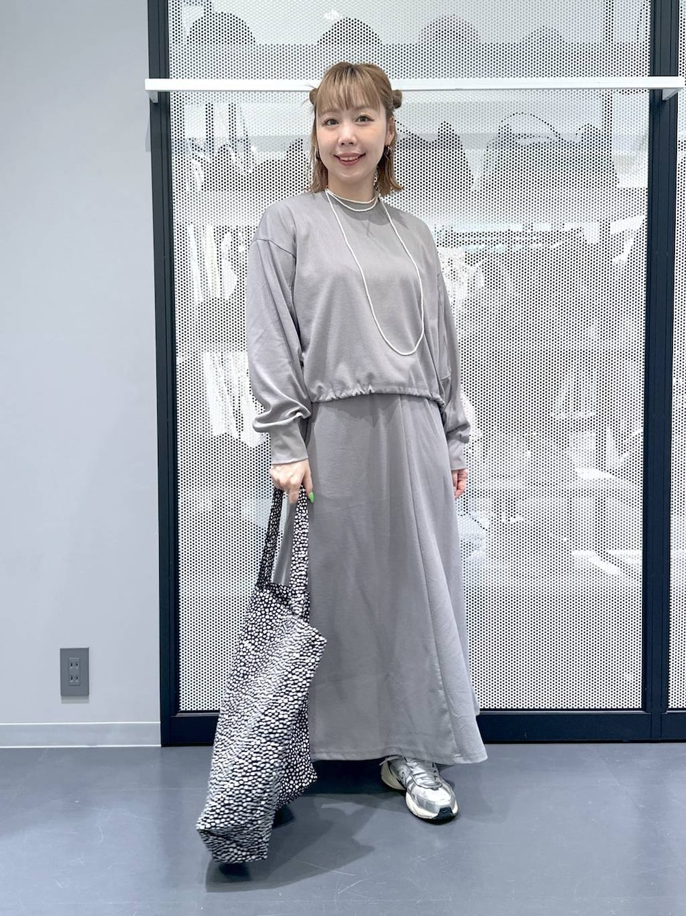 グレー系のスカート、グレー系のTシャツ/カットソー、ブラック系のトートバッグを着用したレディースの春コーディネートの1枚目の写真