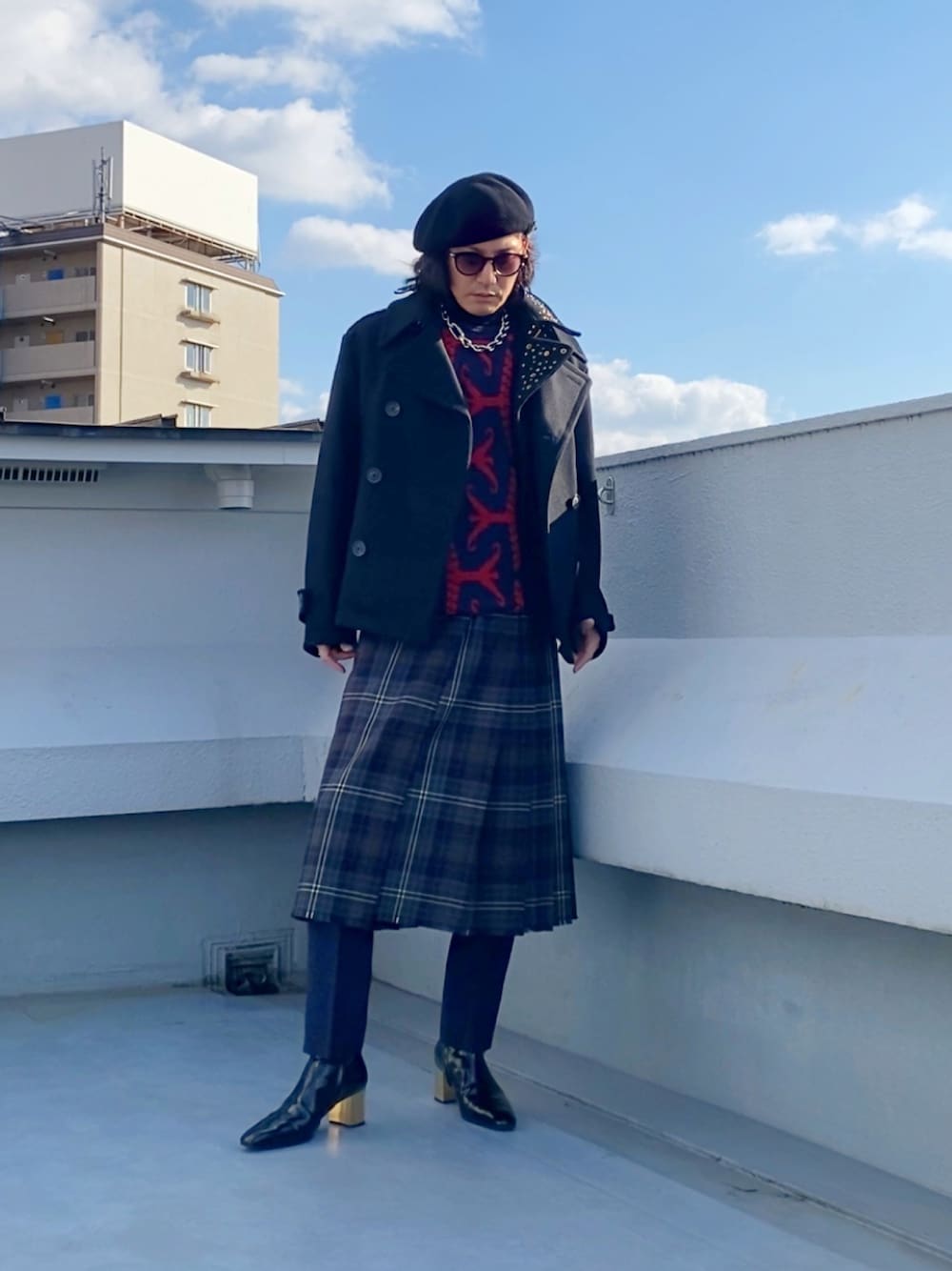 ブラック系のピーコート、レッド系のニット/セーター、ブラウン系のスカートを着用したメンズの冬コーディネートの1枚目の写真