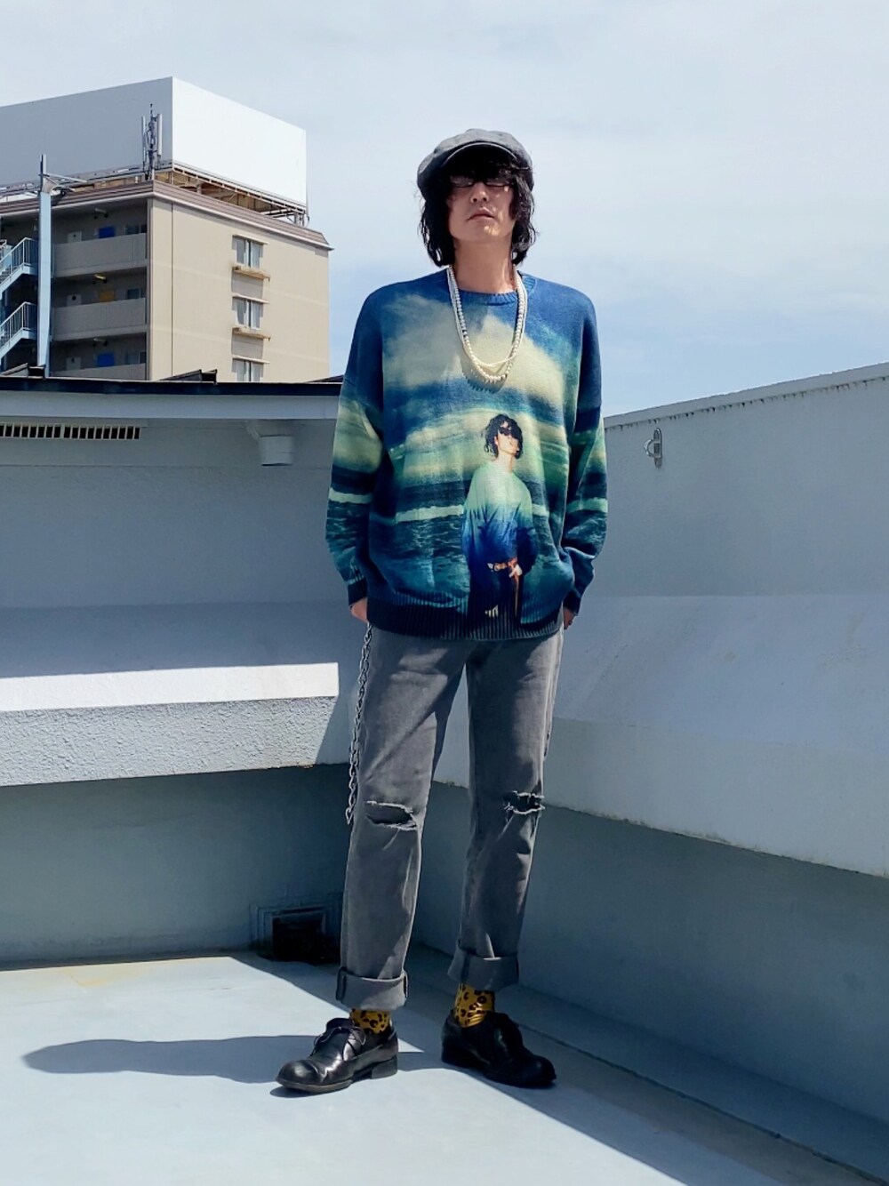 ブルー系のニット/セーター、グレー系のデニムパンツ、ブラック系のドレスシューズを着用したメンズの春コーディネートの1枚目の写真