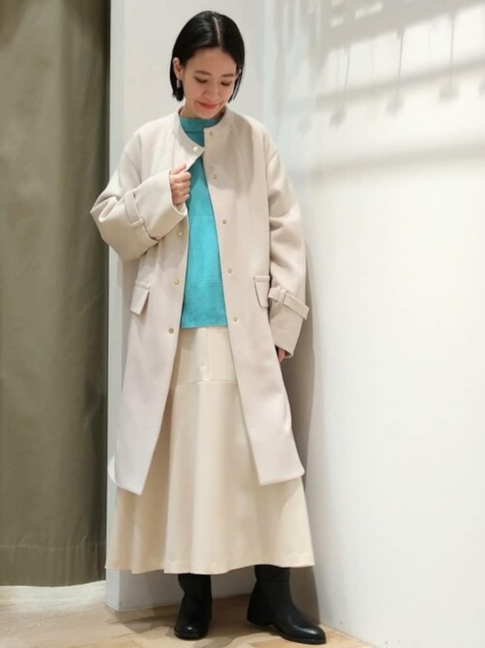 ベージュ系のノーカラーコート、グリーン系のカーディガン/ボレロ、ホワイト系のTシャツ/カットソーを着用したレディースの冬コーディネートの1枚目の写真